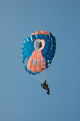 Round parachute against the blue sky in an unusual color scheme. Imitation of a two-color film...