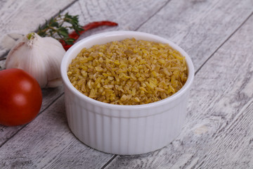 Raw bulgur in the bowl with tomatoes and garlic