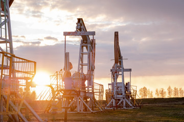 Fototapeta na wymiar Oil well at sunset. Oil production by a rocker at sunset. Rocking machine for oil