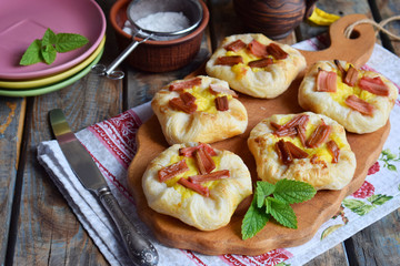 Mini pies made of puff pastry, custard and caramelized rhubarb. Homemade baking. Delicious freshly baked cookies. Rustic photo.