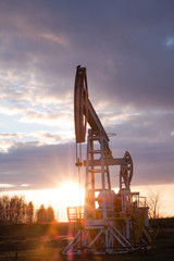 Oil well at sunset. Oil production by a rocker at sunset. Rocking machine for oil