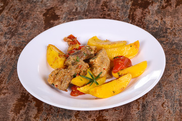 Baked pork meat with potao and tomato