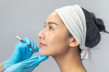 cosmetic botox injection in the face, beauty surgery : Amazing girl teen hat at studio background and looking right, close up, plastic surgery concept, doctor's hand in glove making marks on patients 
