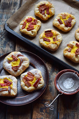 Mini pies made of puff pastry, custard and caramelized rhubarb. Homemade baking. Delicious freshly baked cookies. Rustic photo.