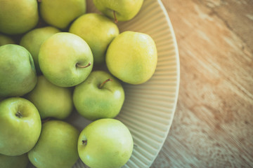 Fresh green apples in bowl on wooden background