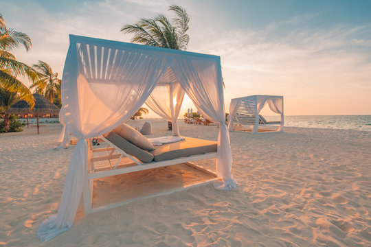 White beach canopies at sunset. Luxury beach tents at luxurious beach resort. Summer beach concept, relaxation and tranquility design