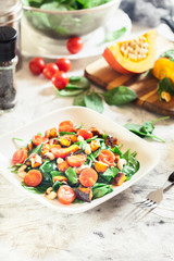 Roasted pumpkin salad with spinach, tomatoes and nuts