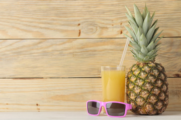 Ripe pineapple fruit and pineapple juice and sunglasses on a natural wooden background. summer. space for text