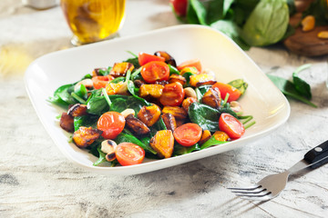 Roasted pumpkin salad with spinach, tomatoes and nuts