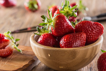 Juicy washed strawberries in wooden bowl on kitchen table