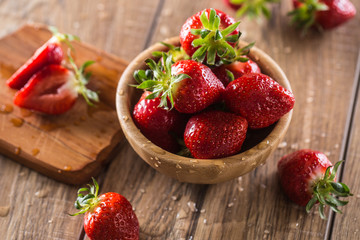 Juicy washed strawberries in wooden bowl on kitchen table