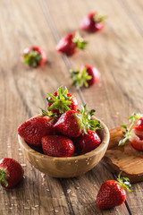Juicy washed strawberries in wooden bowl on kitchen table