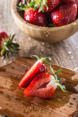 Juicy washed strawberries in wooden bowl on kitchen table