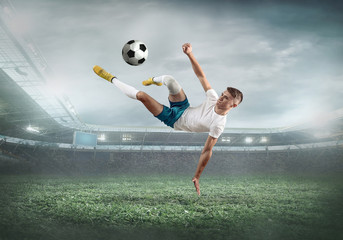 Fototapeta na wymiar Soccer player on a football field in dynamic action at summer da