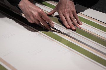 Rome, Italy.Print and fashion industry working together. Close up of a cobbler assembling a dress with black and colored printed fabrics. Cutting prcoess before stitching. Artisan and fashion concept.