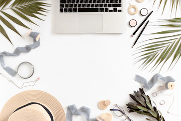 Workspace with laptop, green leaves, cosmetics and accessories with copy space