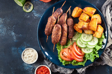 Grilled shish kebab served with fried potatoes
