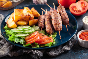 Grilled shish kebab served with fried potatoes