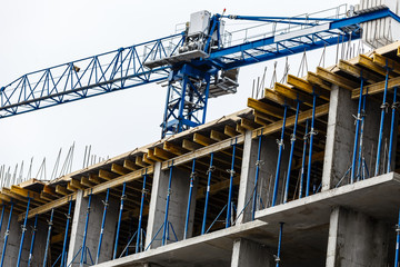 Building crane and building under construction against blue sky