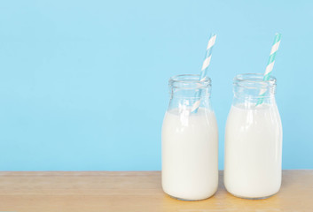 Bottle of fresh milk with straw on light blue background with copy space, food healthy concept