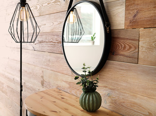 Table and lamp near wooden wall with mirror