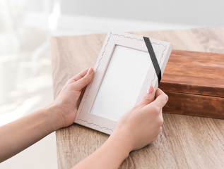 Woman holding empty frame with black ribbon and pining for dead relative