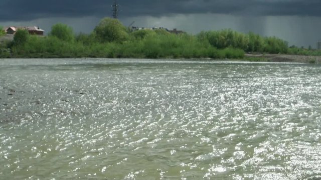 Mountain river in the rays of the sun against the backdrop of the thunder sky, background