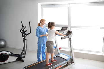 Physiotherapist working with little girl in rehabilitation center