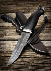 hunting knife handmade on a brown wooden background. Leather Sheath Handmade