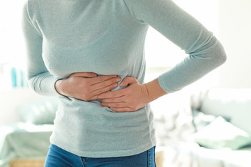 Young woman suffering from stomachache at home