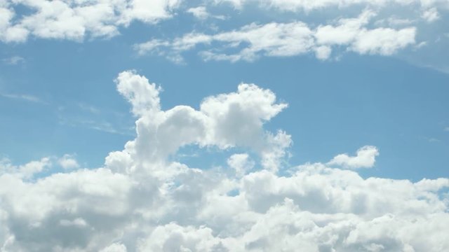 White clouds are moving around across the blue sky,  time lapse