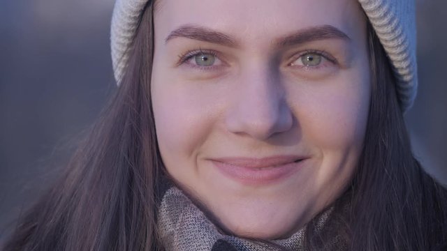 Portrait of a young attractive smiling woman with green eyes who is looking at camera and happily laughing with a lake in the city center on background in slow motion close up 4K video.