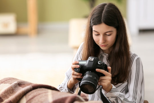 Young girl with modern photo camera at home
