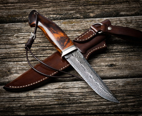 hunting knife handmade on a brown wooden background. Leather Sheath Handmade