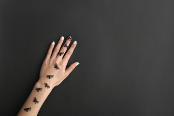 Female hand with stylish manicure and spiders on dark background