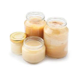 Jars with different healthy baby food on white background