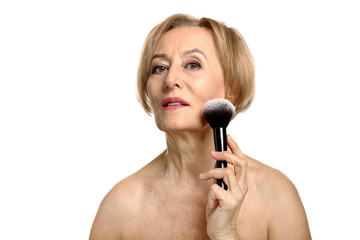 Portrait of beautiful mature woman with makeup brush on white background