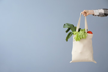 Female hand with eco bag on grey background. Zero waste concept