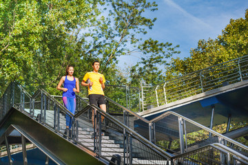 Sporty couple running downstairs at city park