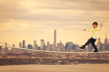 Little black boy walking on the rope over New York