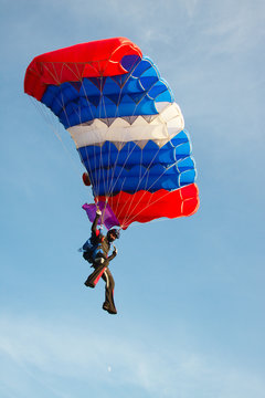 Skydiver with a bright parachute against a sky background with clouds close-up.