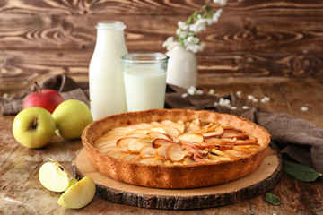 Tasty apple pie, bottle and glass of milk on table