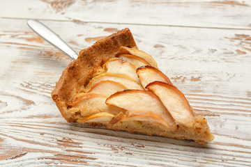 Piece of tasty apple pie on wooden background
