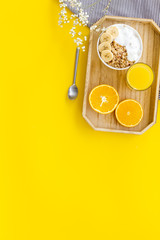 Bright breakfast with granola and orange juice on yellow background top view mockup