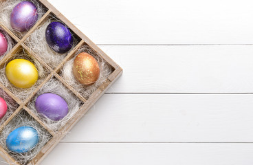 Box with beautiful Easter eggs on white wooden background