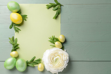 Beautiful Easter eggs, flower and blank card on wooden background