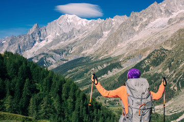 Fototapeta na wymiar woman hiker standing on a mountain background, Mont Blanc massif. Travel around Mont Blanc with a backpack.
