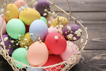Basket with beautiful Easter eggs on wooden background