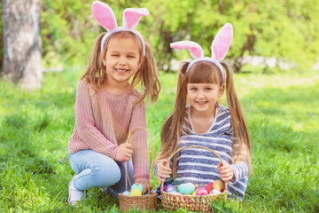 Little children with Easter eggs and bunny ears in park