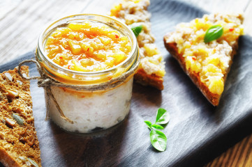 a glass jar of chicken rillettes with pineapple and chili jam along with the rillettes on grain...
